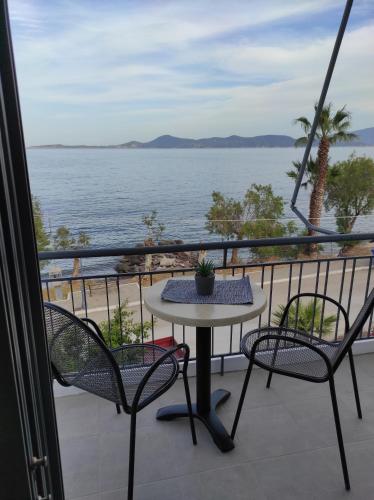 een tafel en stoelen op een balkon met uitzicht op de oceaan bij Dolora's in Methana