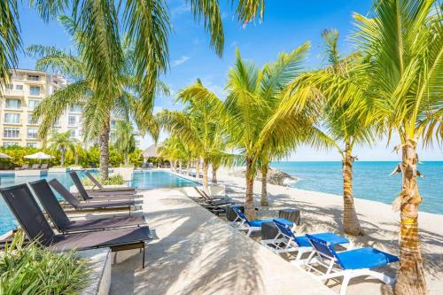 a resort pool with chairs and palm trees and the ocean at Laguna Lake House - Private Pool - Sleeps 12 - Elegant in Playa Blanca