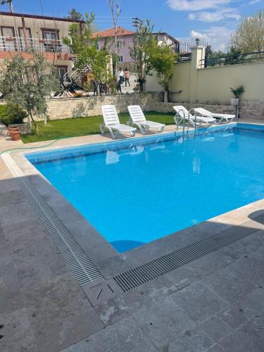 a large blue swimming pool with lounge chairs in a yard at Sirius Pamukkale in Pamukkale