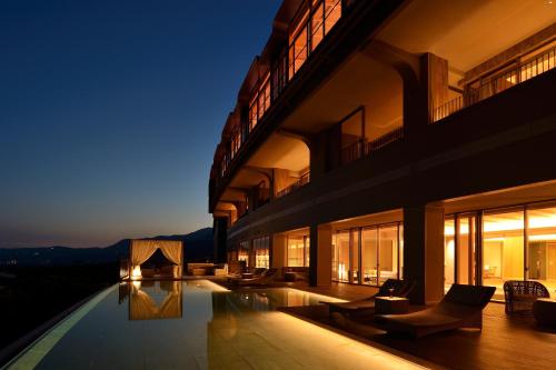 um grande edifício com piscina à noite em KAMENOI HOTEL Izukogen em Ito