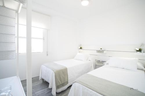 a white room with two beds and a mirror at Balcón a Doñana in Sanlúcar de Barrameda