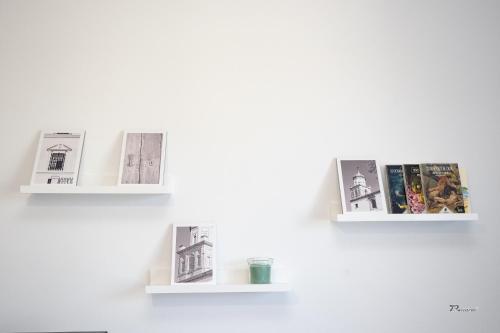 three shelves on a white wall with books at Balcón a Doñana in Sanlúcar de Barrameda