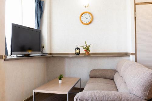 a living room with a couch and a clock on the wall at Goto Conkana Kingdom in Goto
