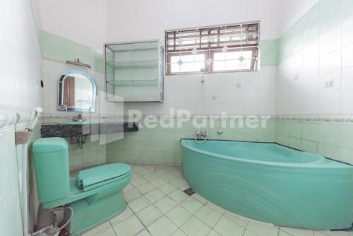 a bathroom with a blue tub and a toilet at Biru Homestay Bandung Mitra RedDoorz in Bandung