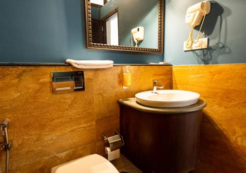 een badkamer met een wastafel, een toilet en een spiegel bij Bloom Boutique Waterfront Fort Kochi in Cochin