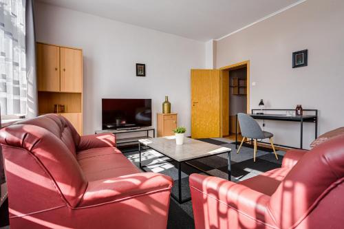 a living room with red leather furniture and a tv at Hotel Sowa in Elblag