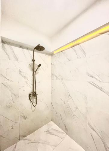 y baño con ducha y paredes de mármol blanco. en Burgundy Guest Suite, en Manila