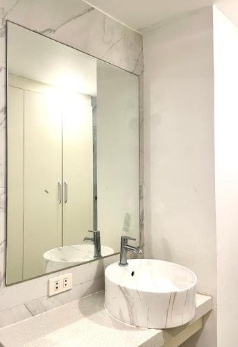 a white bathroom with a sink and a mirror at Burgundy Guest Suite in Manila
