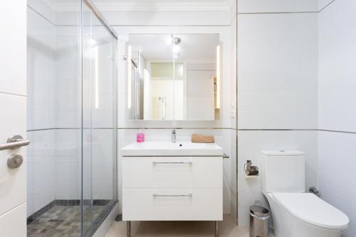 a white bathroom with a toilet and a sink at AMAZING SEASIGHTS - TENERIFE in Costa Del Silencio