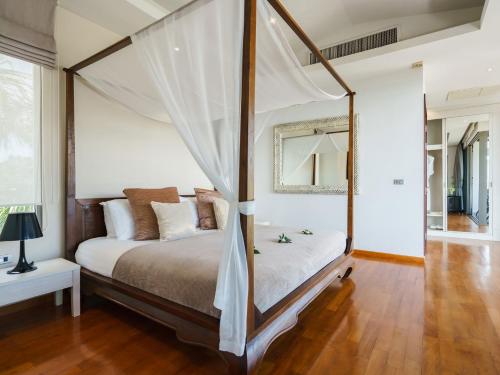 una camera con letto a baldacchino e pavimento in legno di Inasia Beach Villa by Elite Havens a Lipa Noi