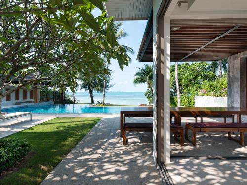 an outdoor patio with a table and benches overlooking the ocean at Inasia Beach Villa by Elite Havens in Lipa Noi