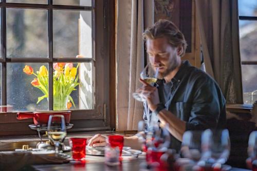 a man sitting at a table drinking a glass of wine at Le Coucou Hotel Restaurant & Lounge-Bar in Montreux