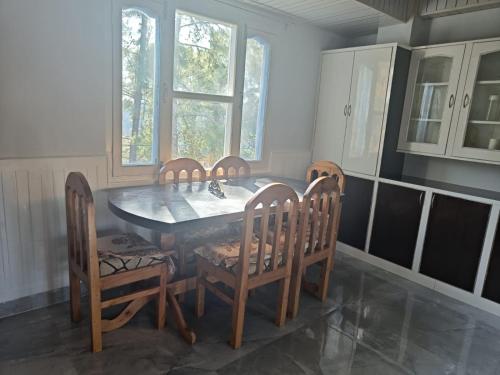 a dining room with a table and chairs and windows at Hill Side Inn in Shimla