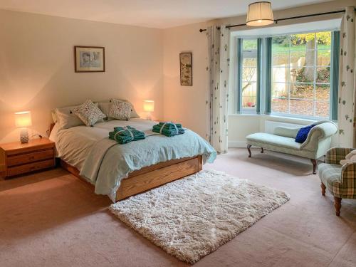 a bedroom with a bed and a chair and a window at Milnhead Cottage in Amisfield Town