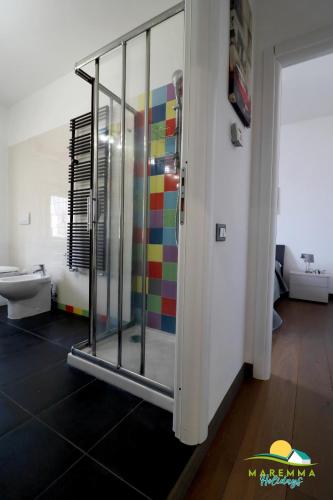 La salle de bains est pourvue d'une douche et d'un mur coloré. dans l'établissement Maremma Holidays -Trento Apartment, à Follonica