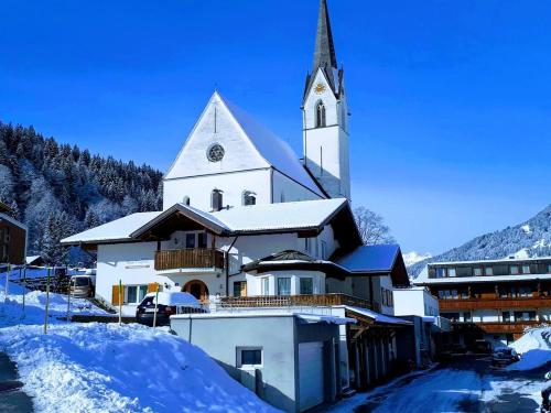 a large white church with a clock tower in the snow at Haus Dagmar in Silbertal