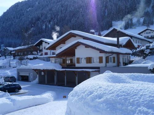 a house covered in snow in front of a mountain at Haus Dagmar in Silbertal