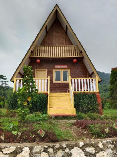 uma pequena casa de madeira com um alpendre e escadas em Duren medan Twbm Rumpin em Sawah