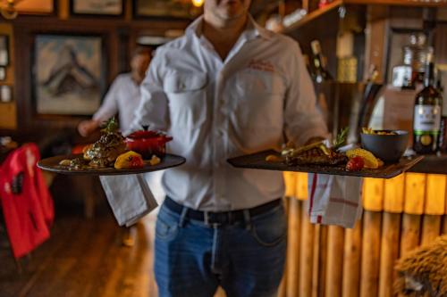 a man is holding two plates of food at Le Coucou Hotel Restaurant & Lounge-Bar in Montreux