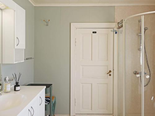 uma casa de banho com um chuveiro e uma porta branca em Holiday home LYNGØR 