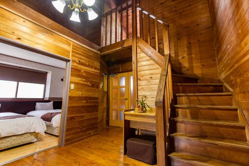 a bedroom with wooden walls and a bed and a staircase at Goto Conkana Kingdom in Goto