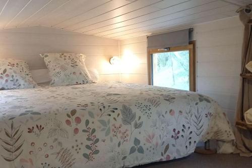 フィジャックにあるMini maison tiny house et son bain nordiqueのベッドルーム1室(白い掛け布団、窓付)