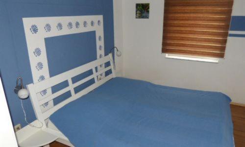 Habitación con cama azul y blanca y ventana en Ferienhaus Luppath, en Poseritz
