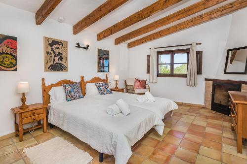 a bedroom with a large white bed and a fireplace at Noguera -Pollensa in Pollença