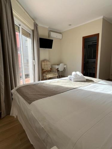a bedroom with a large white bed with a window at Hotel Ramis fundado en 1969 in Ondara