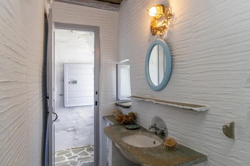 a bathroom with a sink and a mirror on the wall at Traditional Tinos Olive Mill House in Chatzirados