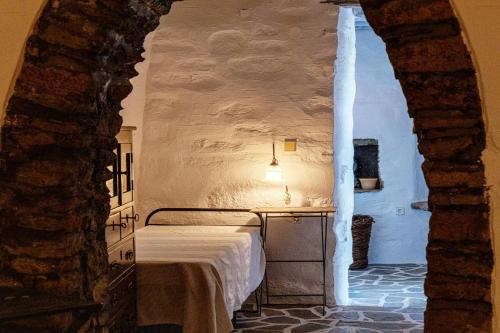 a bedroom with a bed in a stone wall at Traditional Tinos Olive Mill House in Khatzirádhos