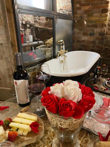 un tavolo con un vaso di rose e una bottiglia di vino di Al Silter a Capriate San Gervasio