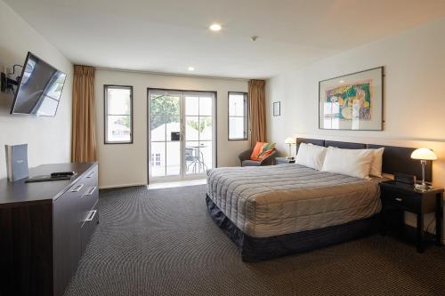 a bedroom with a bed and a desk and a television at Pavilions Hotel in Christchurch