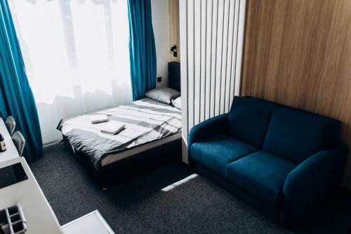 a small room with a bed and a blue chair at RESA apart - нові smart-квартири біля річки in Uzhhorod