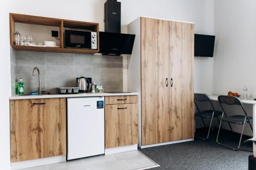 a kitchen with a white refrigerator and wooden cabinets at RESA apart - нові smart-квартири біля річки in Uzhhorod