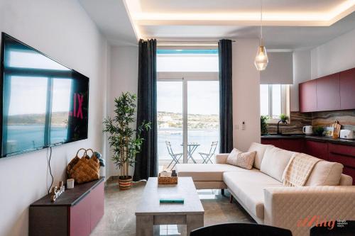 a living room with a white couch and a large window at Seashore Stays - Stunning apartments right by the sea in St. Paul's Bay