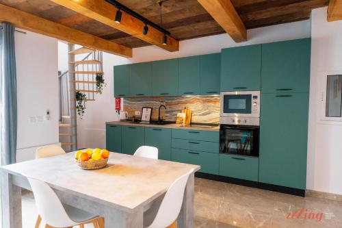 a kitchen with green cabinets and a table with a bowl of fruit at Seashore Stays - Stunning apartments right by the sea in St. Paul's Bay