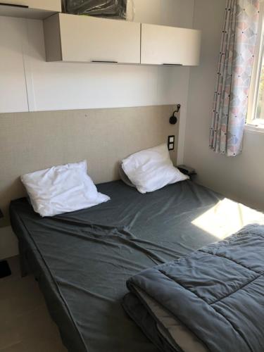 uma cama com duas almofadas num quarto em Camping le Castellas em Sète