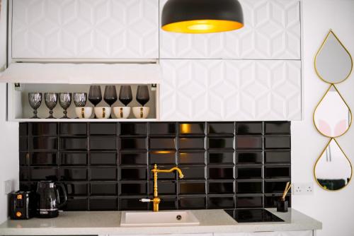 een keuken met een wastafel en een zwart-witte tegelmuur bij New Leventis Luxury Κing Suite 41-Central Location in Ayia Napa