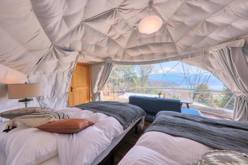 sypialnia z 2 łóżkami w namiocie z oknem w obiekcie Retreat Camp Mahoroba w mieście Fujikawaguchiko