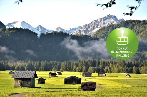 a green field with houses and mountains in the background at Hotel Cafe Fuggerhof in Oberstdorf