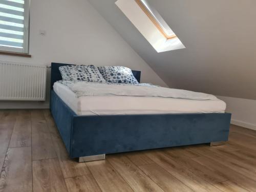 um quarto com uma cama azul num sótão em Apartament w sosnowym lesie em Międzywodzie