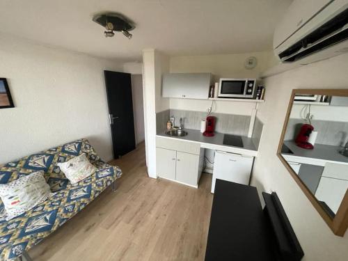un petit salon avec un canapé et une cuisine dans l'établissement Plage du Grazel & vue sur les Chalets de Gruissan, à Gruissan