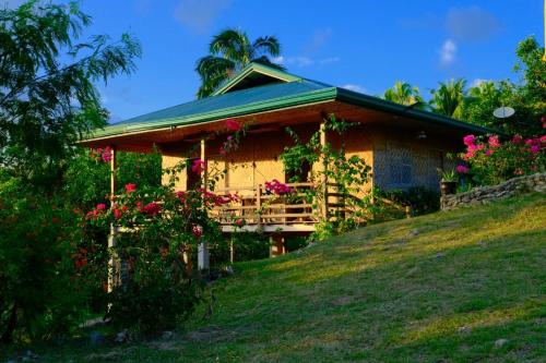 a house on a hill with flowers in front of it at Marquis garden Eco-cottages in Tocdoc