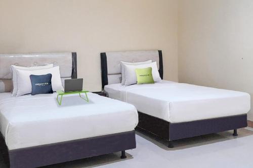 duas camas sentadas uma ao lado da outra num quarto em Urbanview Hotel Istana Bangun Jagad Indramayu by RedDoorz em Indramayu