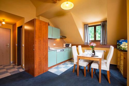 uma cozinha com uma mesa e cadeiras brancas num quarto em Yellow Ski Apartments em Rokytnice nad Jizerou