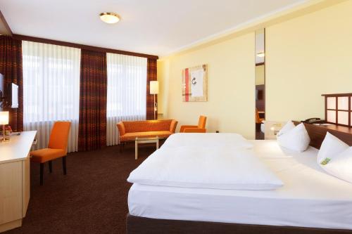 a hotel room with two beds and a table and chairs at Best Western Hotel Augusta in Augsburg