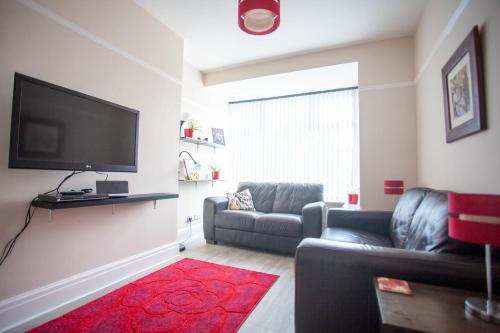 a living room with a couch and a flat screen tv at Dalmore - Quiet residence with long driveway at M6 Preston in Samlesbury