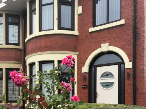 a red brick house with a white door and pink flowers at Dalmore - Quiet residence with long driveway at M6 Preston in Samlesbury