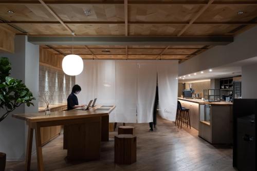 a woman sitting at a table with a laptop at RAKURO Kyoto by THE SHARE HOTELS in Kyoto